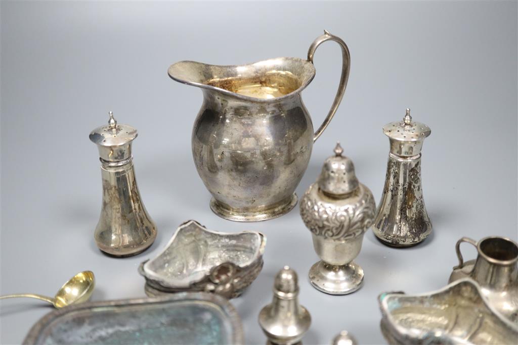 A George V silver cream jug and a collection of small silver and plated condiments and spoons.